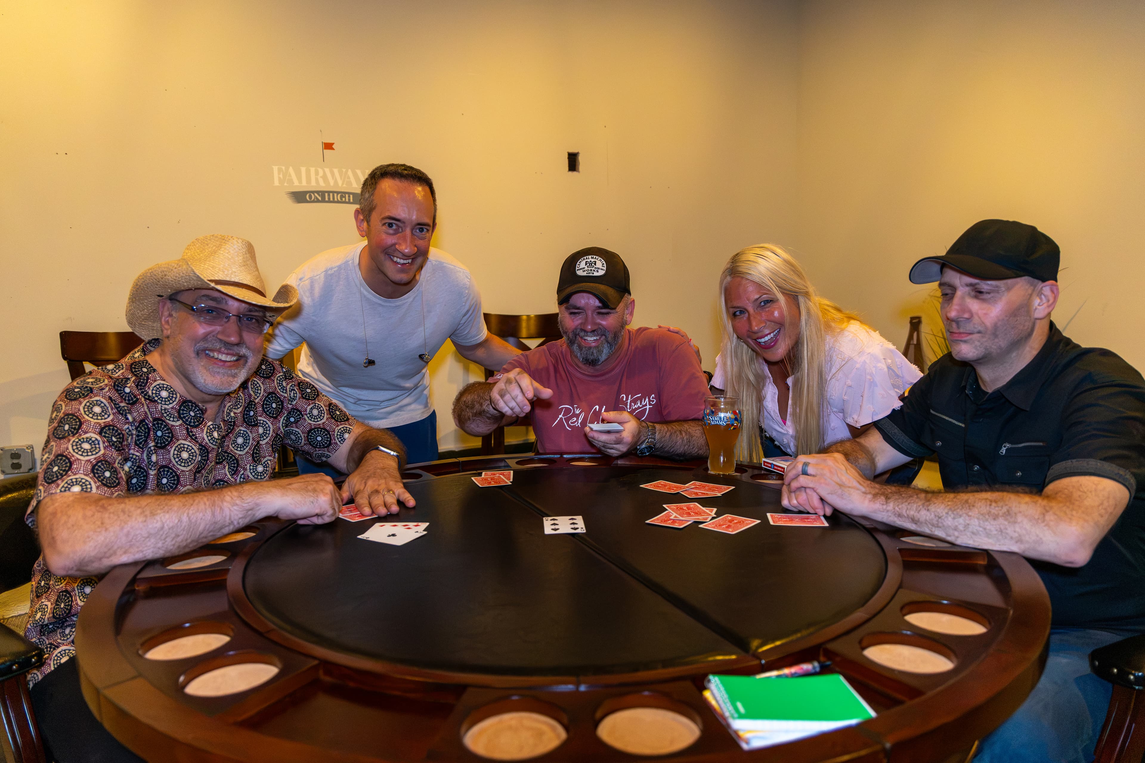 The five band members posing around a card table after a show at Fairways on High