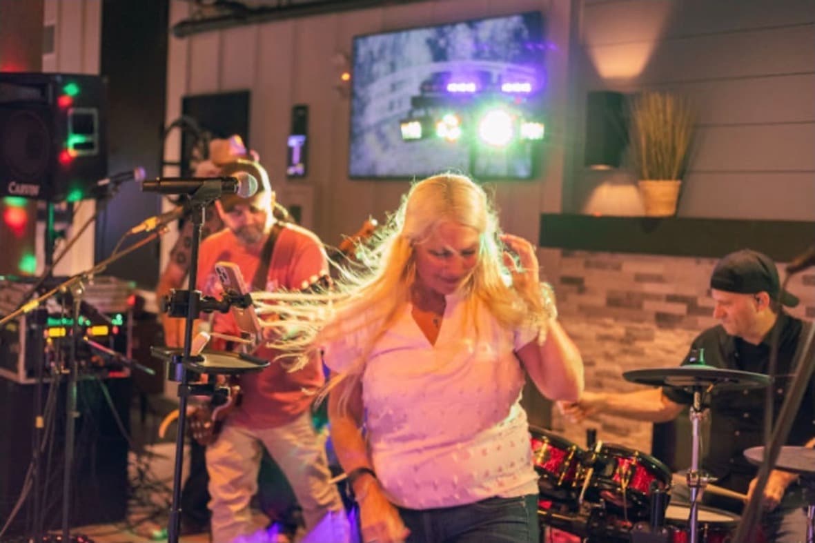 Singer dancing on the indoor stage with colorful lights washing over the band