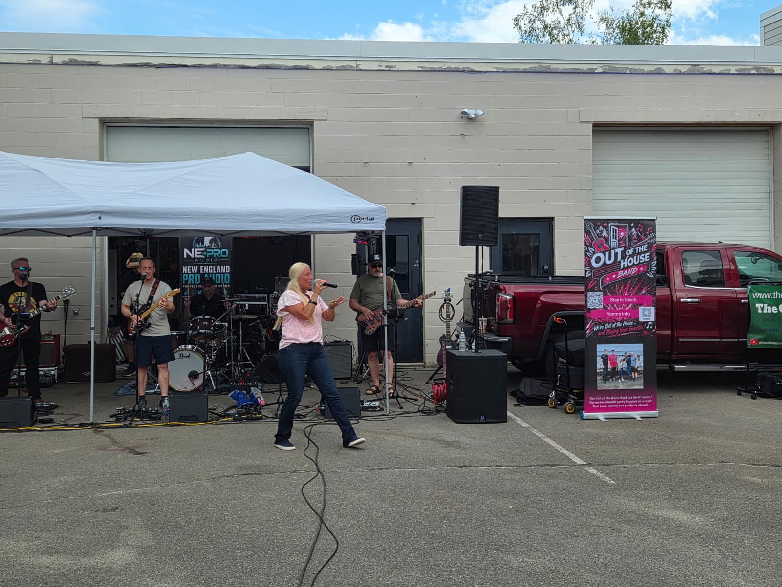 The band performing under a tent at an outdoor daytime gig