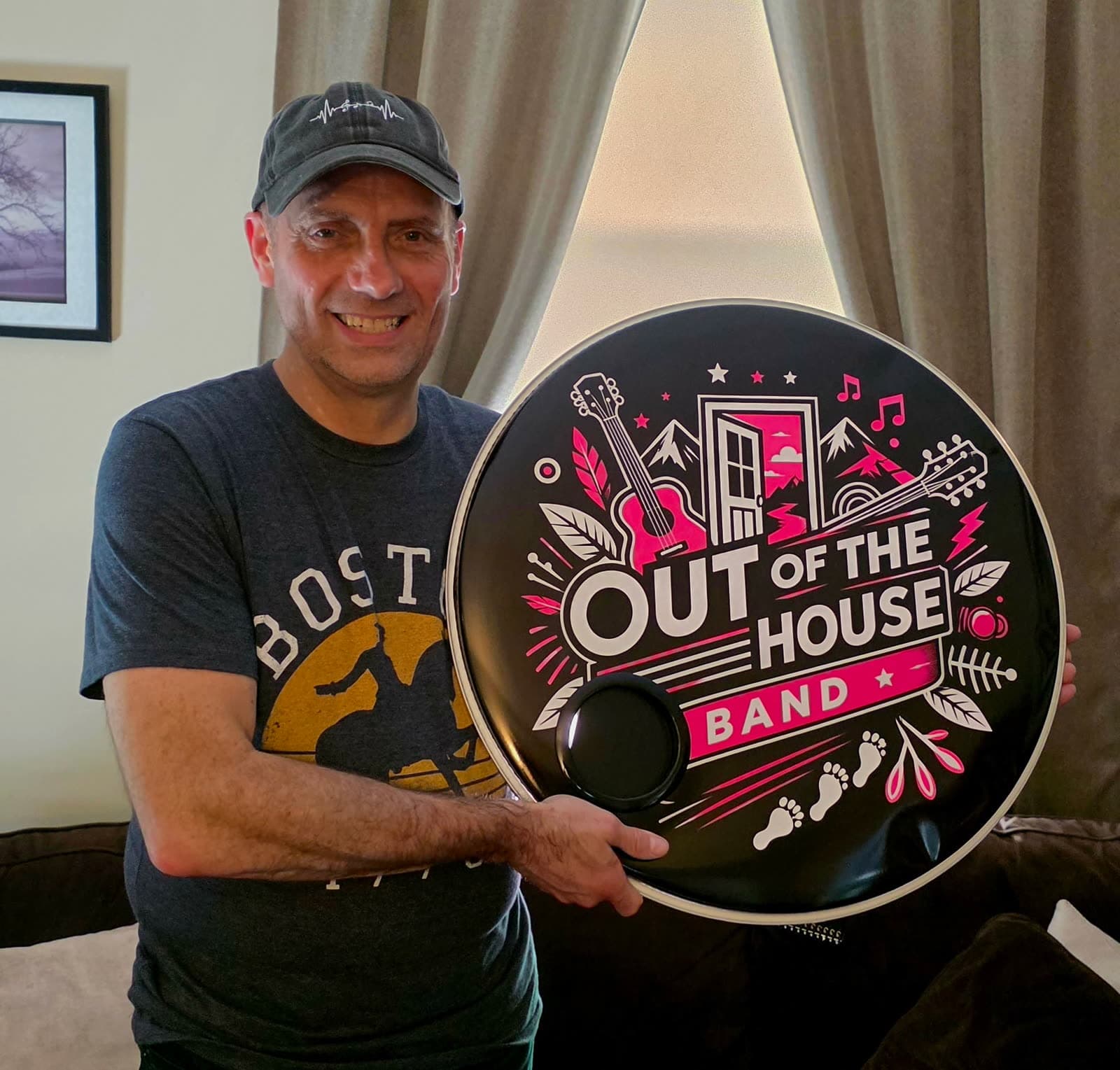 Band member holding up a drumhead printed with the Out of the House Band logo