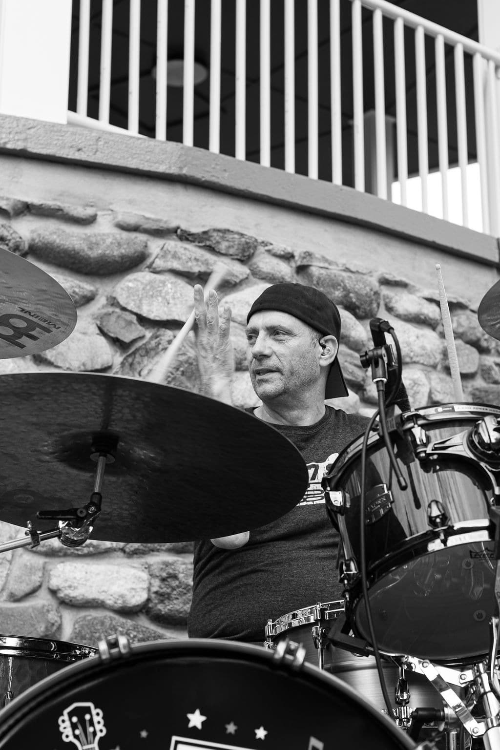 Black-and-white shot of the drummer mid-hit behind the kit