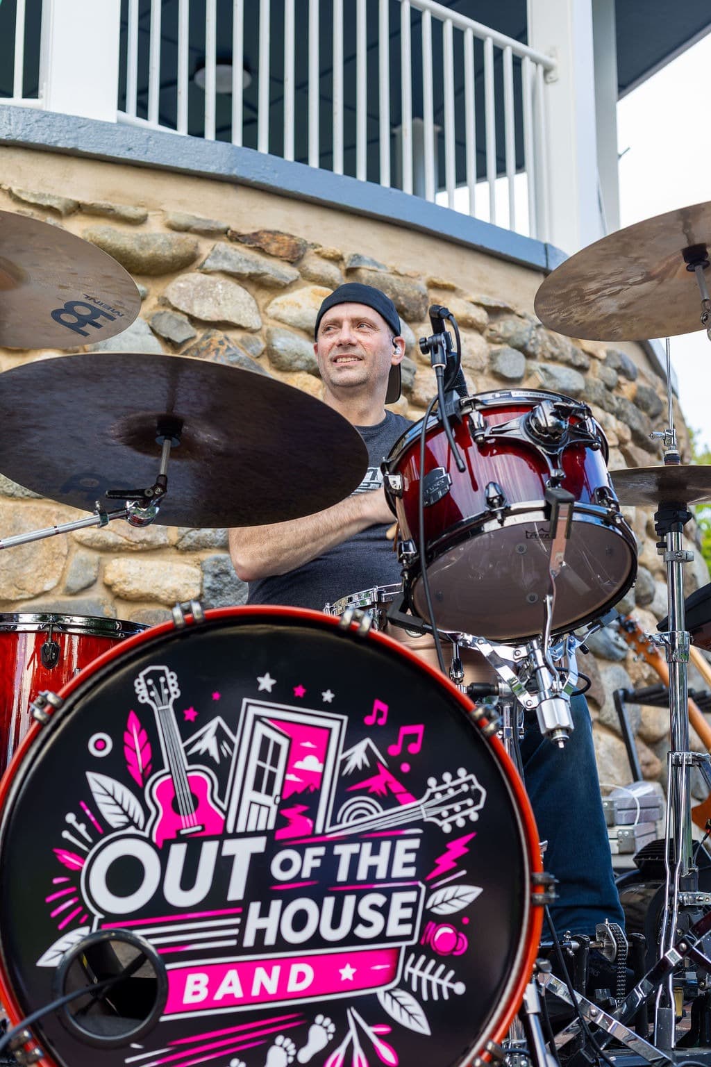 Drummer smiling behind the kit on an outdoor stage in daylight