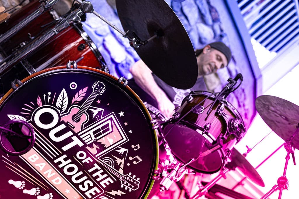Close-up of the band's branded bass drum with the drummer under purple stage lights