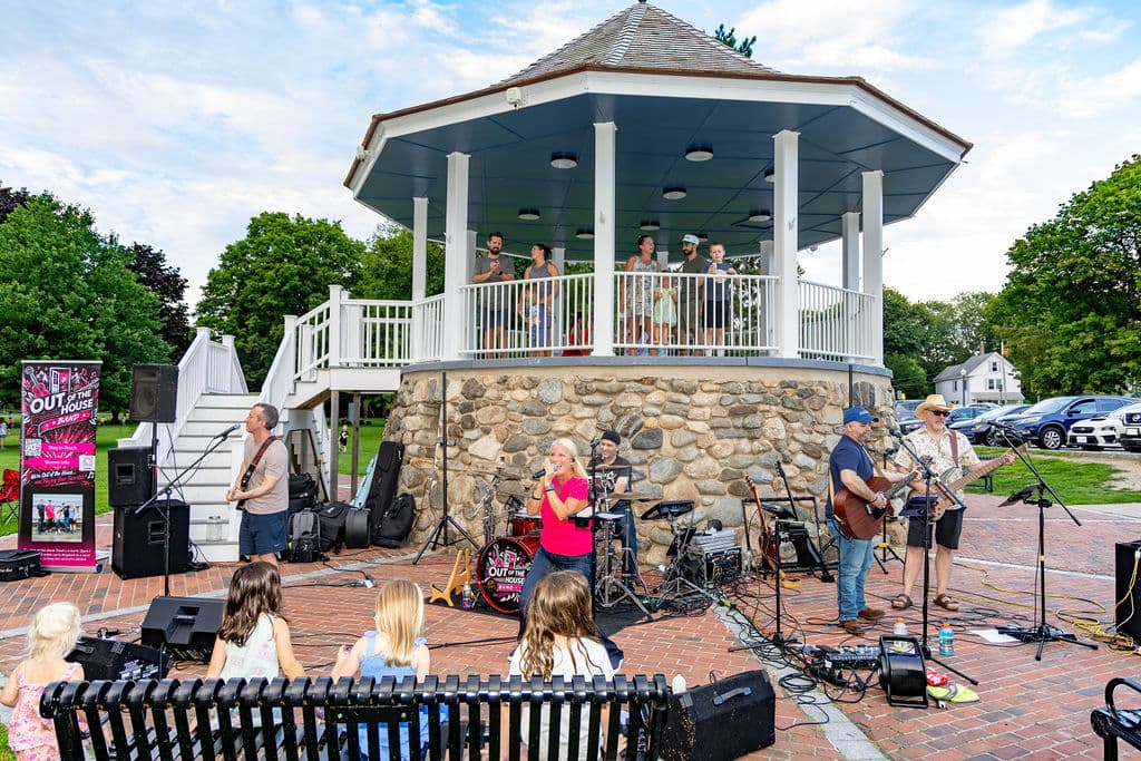 The band performing from a park gazebo bandstand for a packed town common crowd