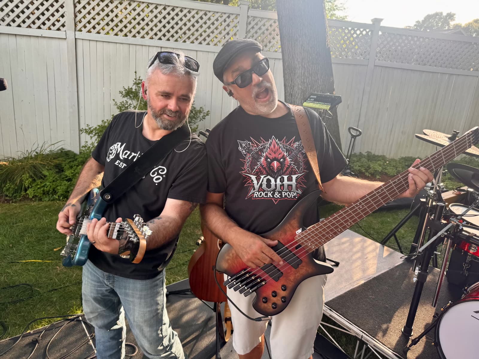 Two guitarists playing together at an outdoor backyard show
