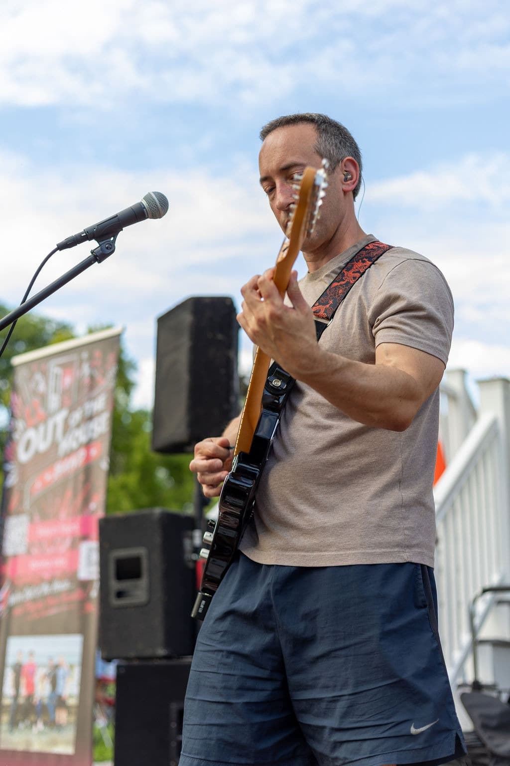 Guitarist soloing outdoors with the band's event banner in the background