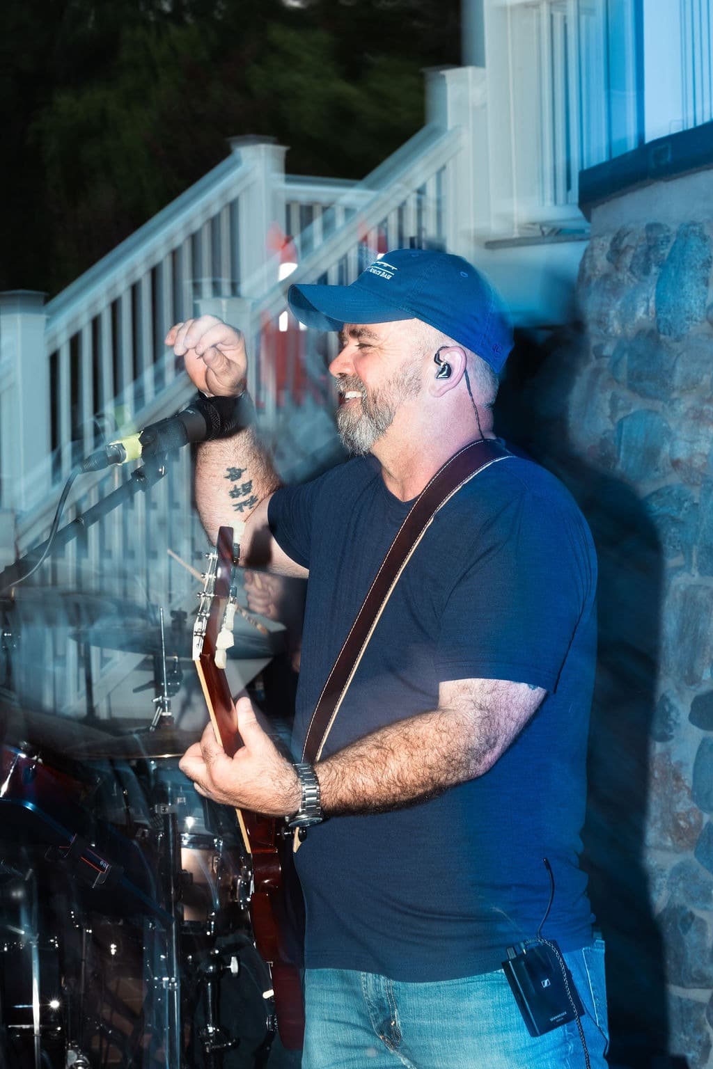Artistic long-exposure shot of the guitarist singing, capturing the motion of the performance