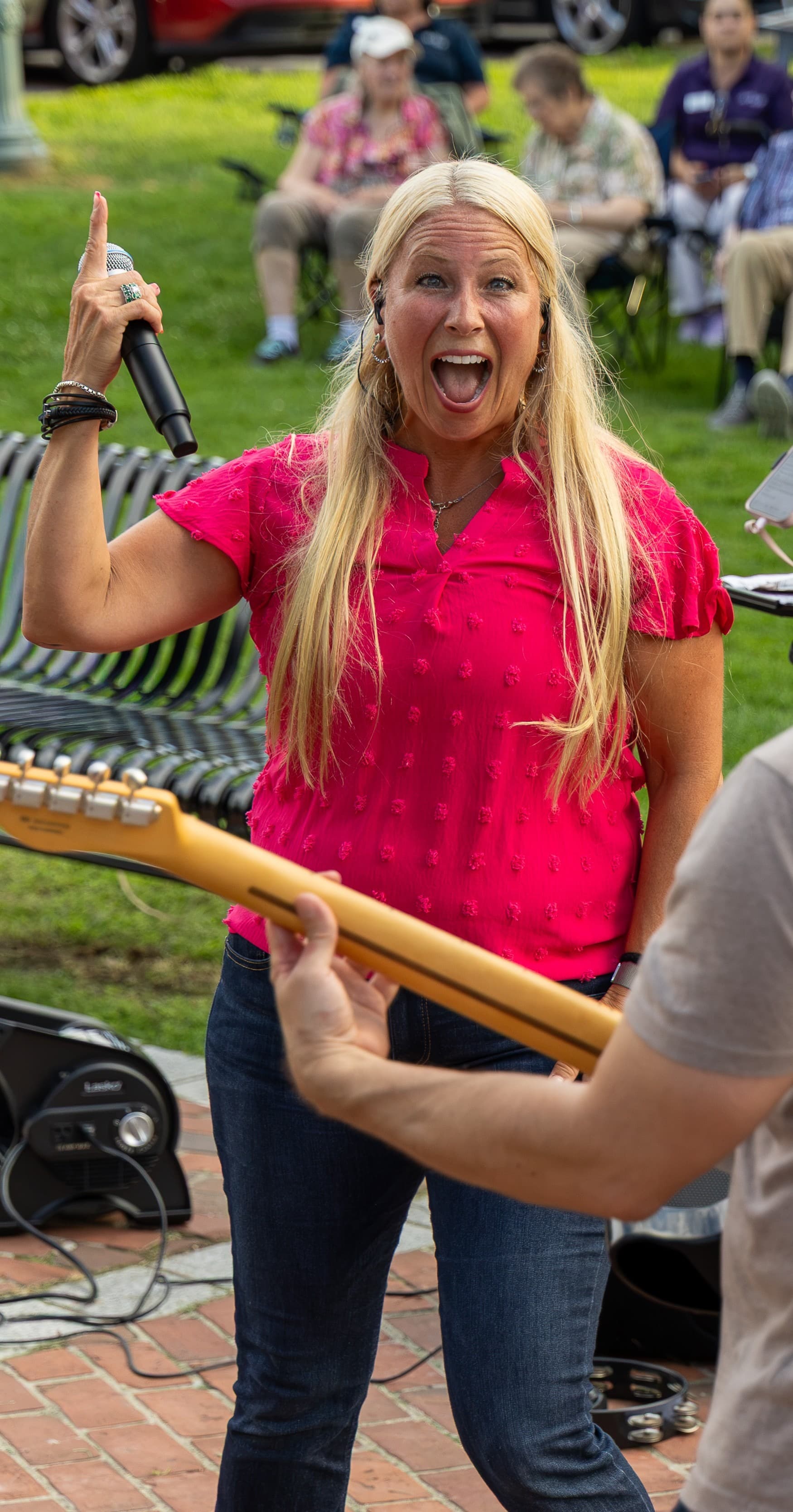 Lead singer shouting into the mic with the crowd looking on behind her