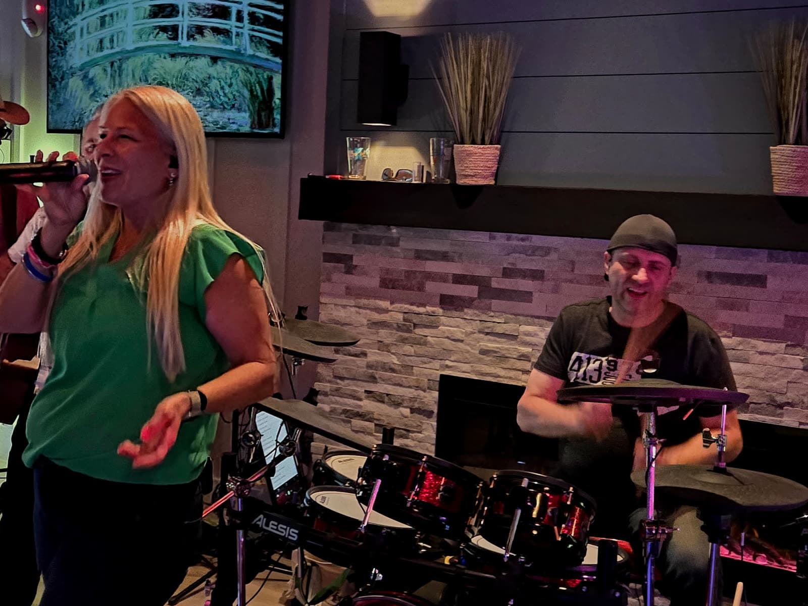 Lead singer performing in close-up with the drummer smiling behind her
