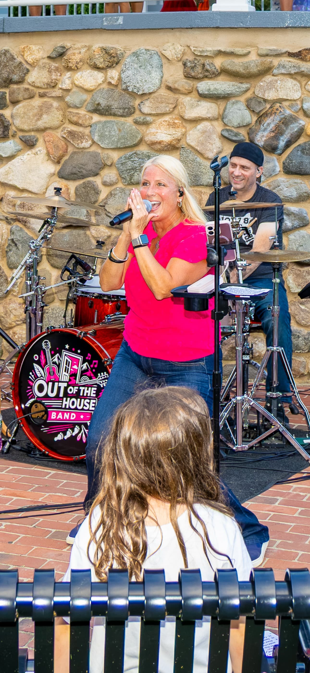 Lead singer performing with a young fan watching from a bench in the foreground