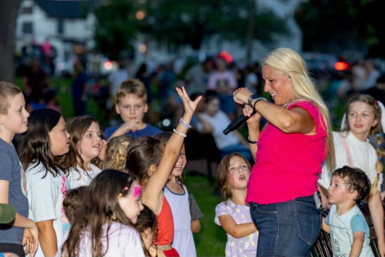 Singer high-fiving a crowd of kids with hands raised at night